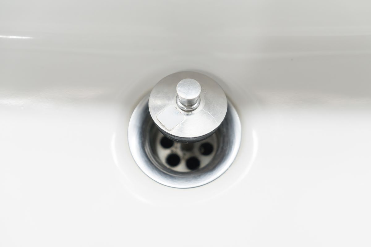 Bonde chromée au fond d'un lavabo en céramique blanche