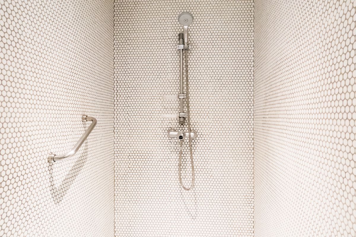 Cabine de douche carrelée de mosaïque blanche, barre de douche et flexible