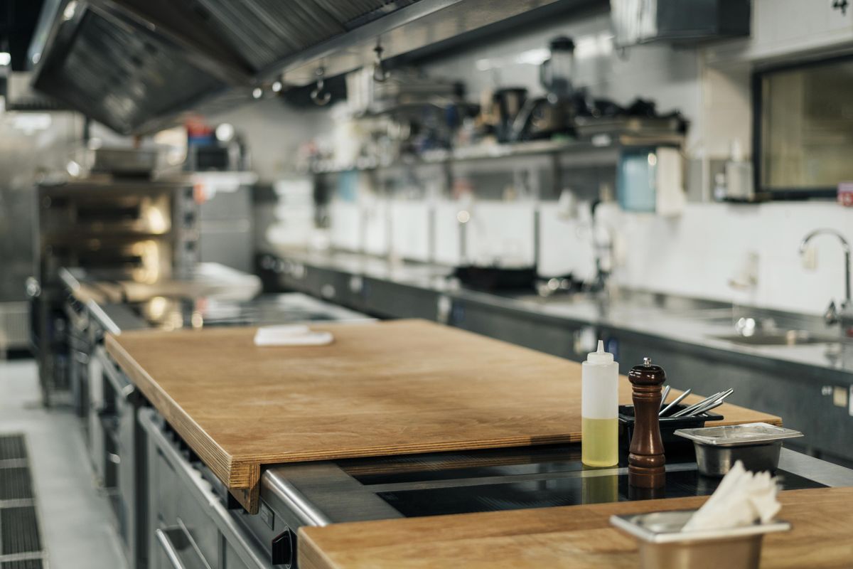 Cuisine de restaurant vide et éclairée, plans inox, hotte et billot central