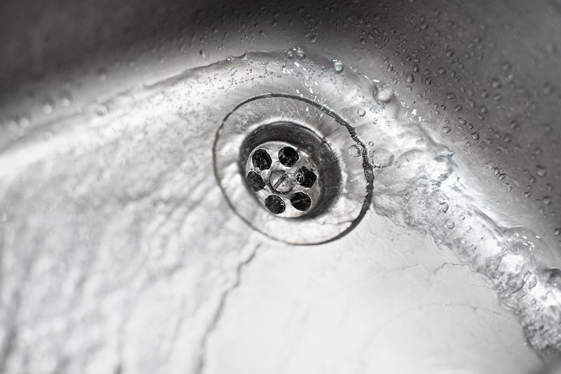 Eau qui tourbillonne et s'évacue franchement par la bonde d'un évier en inox