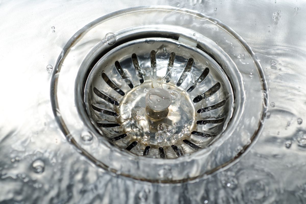 Eau qui tourne au-dessus d'une bonde d'évier en inox