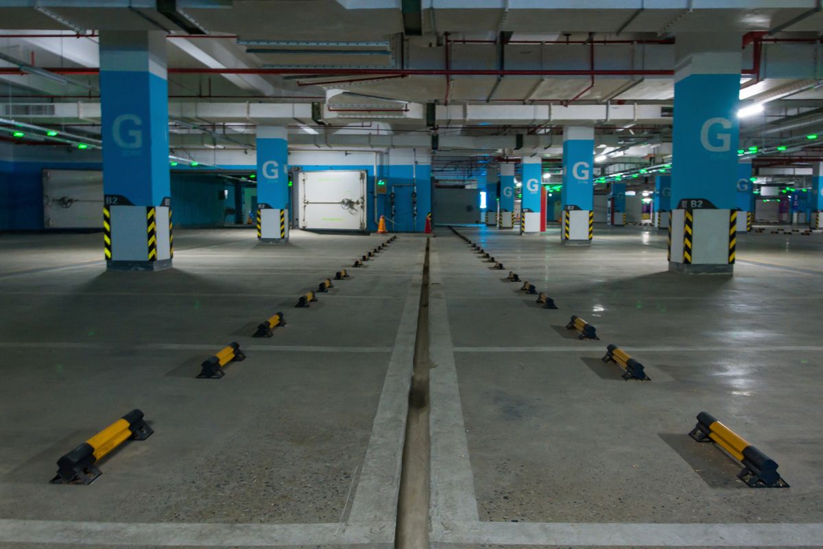 Niveau de parking souterrain vide, parcouru en son centre par un caniveau qui recueille les eaux de sol.