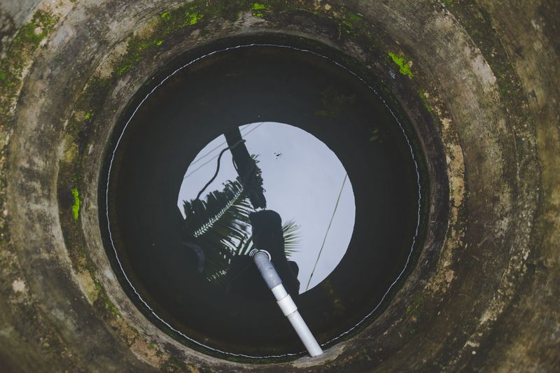 Vue plongeante dans un ouvrage maçonné circulaire, le ciel reflété au fond sur la surface de l'eau
