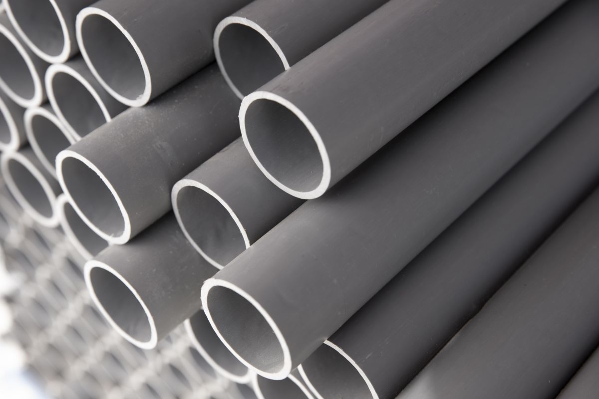 Des tubes en PVC gris de même diamètre sont empilés et vus en biais par leurs extrémités.