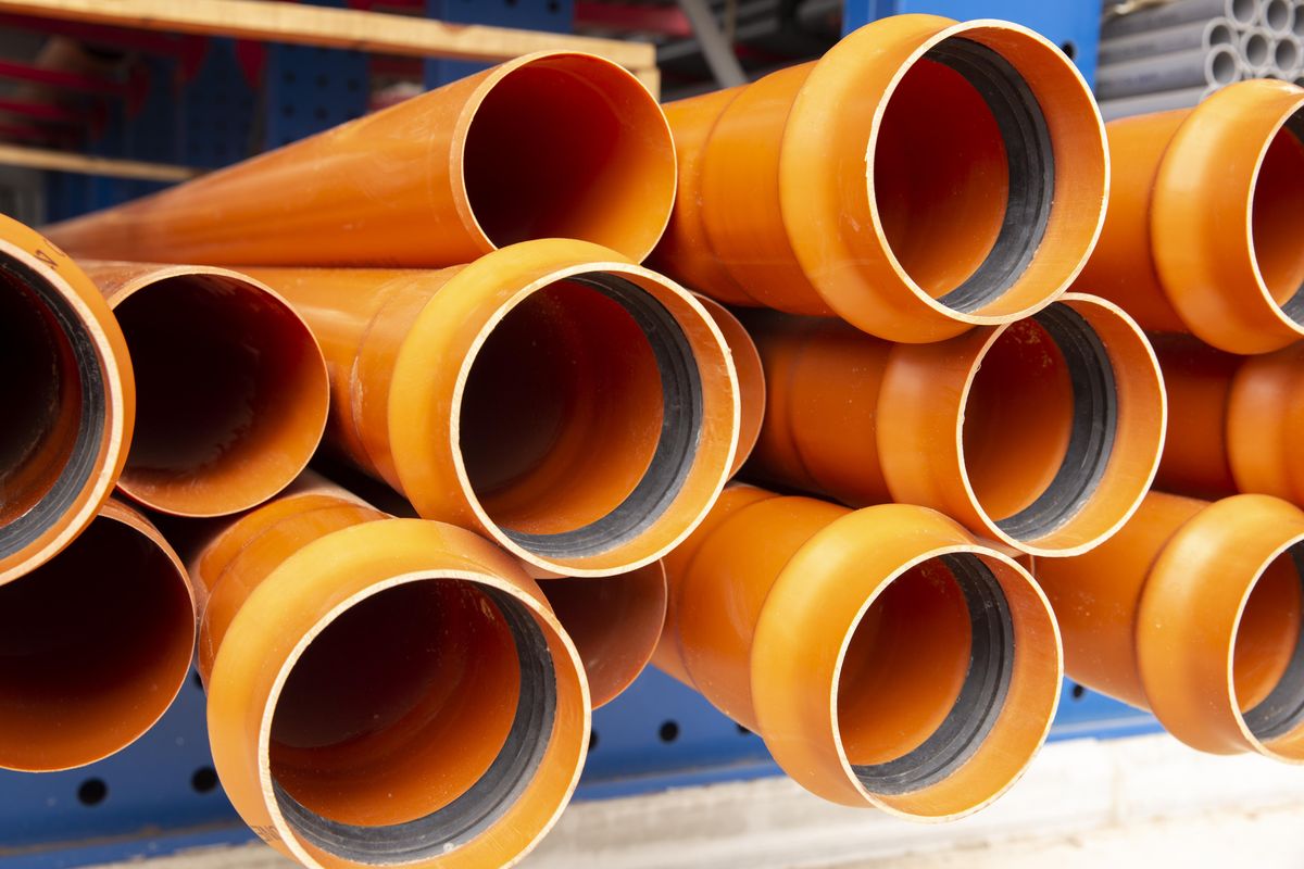 Tuyaux d'évacuation en PVC orange empilés, extrémités à emboîtement et joints noirs bien visibles.